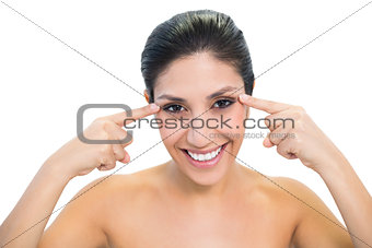 Happy brunette pointing to eyes and looking at camera