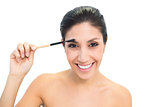 Brunette using an eyebrow brush and smiling