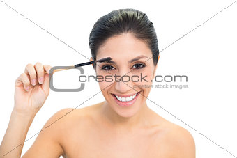 Brunette using an eyebrow brush and smiling