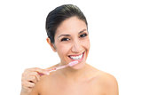 Brunette brushing her teeth and smiling at camera