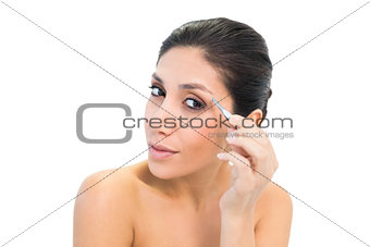 Brunette plucking her eyebrows and looking at camera