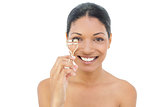 Cheerful black haired model holding eyelash curler