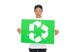 Curious young woman holding recycling sign