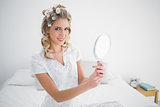 Cheerful blonde holding mirror on cosy bed