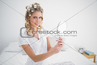 Cheerful blonde holding mirror on cosy bed
