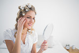 Happy blonde with hair curlers looking at reflection