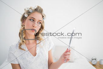 Gorgeous blonde wearing hair curlers looking at reflection while kissing