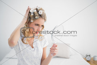 Frowning gorgeous blonde wearing hair curlers posing