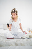 Pretty blonde wearing hair curlers text messaging