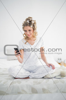 Pretty blonde wearing hair curlers text messaging