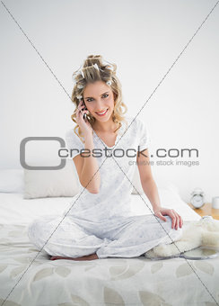 Smiling pretty blonde wearing hair curlers on the phone
