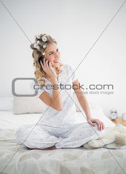 Cheerful pretty blonde wearing hair curlers on the phone