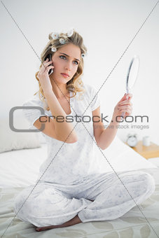 Pensive blonde wearing hair curlers phoning