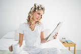 Focused cute blonde wearing hair curlers reading newspaper