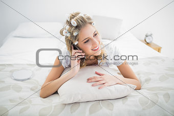 Cheerful blonde wearing hair curlers on the phone