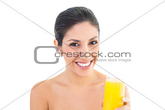 Brunette smiling at camera holding glass of orange juice