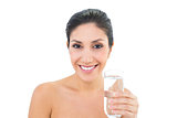Happy brunette holding glass of water and smiling at camera