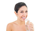 Smiling brunette holding glass of water and looking at camera