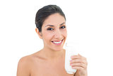 Smiling brunette holding glass of milk and looking at camera