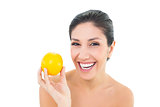Smiling brunette holding an orange and looking at camera