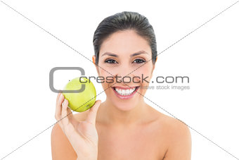Happy brunette holding a green apple and looking at camera