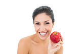 Happy brunette holding a red apple and looking at camera