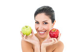 Happy brunette holding red and green apples and looking at camera