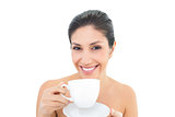 Attractive brunette holding a cup and saucer and smiling at camera