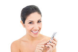 Attractive brunette using a smartphone and smiling at camera
