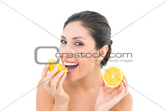 Pretty brunette holding two orange halves and smiling at camera