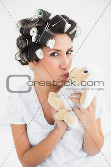 Happy brunette in hair rollers kissing sheep teddy