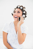 Laughing brunette in hair rollers on the phone on bed
