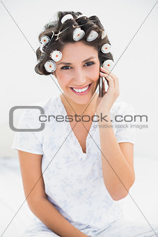 Pretty brunette in hair rollers on the phone on bed