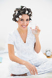 Happy brunette in hair rollers holding glass of water