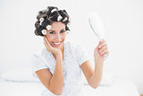 Pretty brunette in hair rollers holding hand mirror