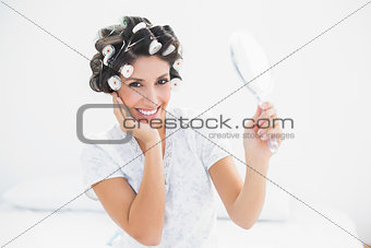 Pretty brunette in hair rollers holding hand mirror