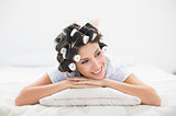Pretty brunette in hair rollers lying on her bed
