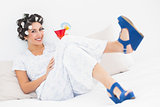 Brunette in hair curlers and wedge shoes holding a cocktail