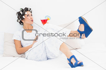 Brunette in hair curlers and wedge shoes having a cocktail