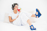 Brunette in hair rollers and wedge shoes drinking a cocktail