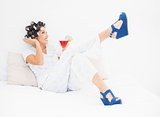 Brunette in hair rollers and wedge shoes holding a cocktail