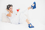 Brunette in hair rollers and wedge shoes holding a cocktail looking at camera