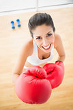Fit woman wearing red boxing gloves smiling at camera