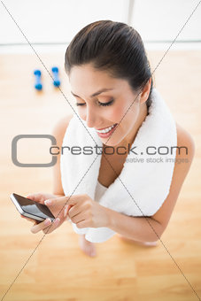 Fit woman using smartphone taking a break from workout