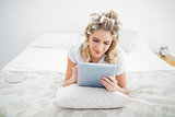 Peaceful pretty blonde wearing hair curlers using tablet pc