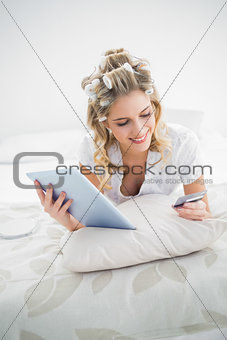 Cheerful pretty blonde wearing hair curlers shopping online