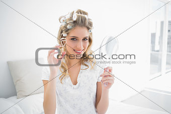 Smiling natural blonde holding eyelash curler