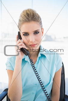 Serious stylish businesswoman answering the phone