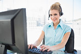 Smiling call centre agent working on computer