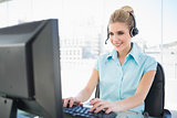 Cheerful call centre agent working on computer